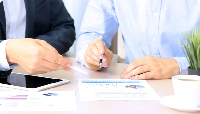 Two people are sitting at a table with papers.