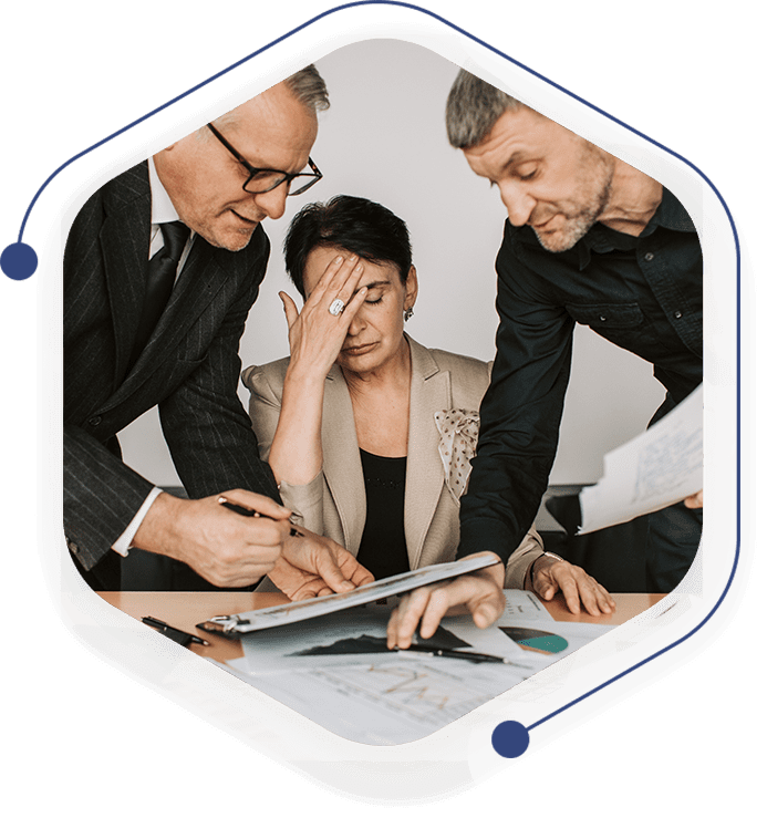 Three people are gathered around a table looking at papers.