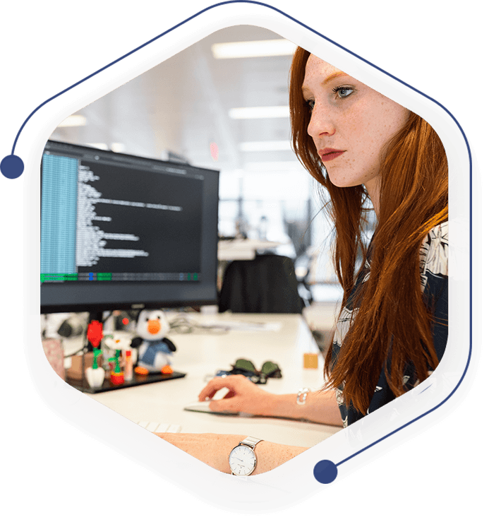 A woman sitting at her computer desk in front of a monitor.