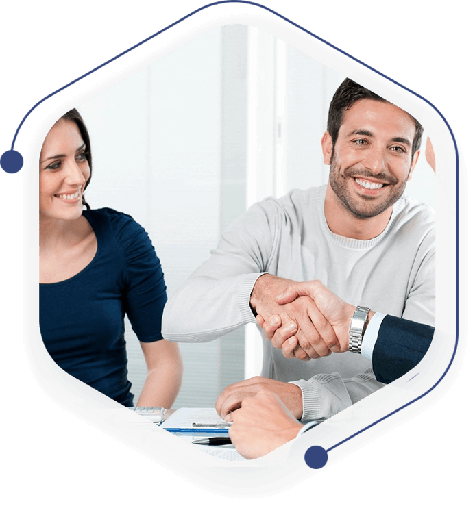 A man and woman shaking hands over a table.