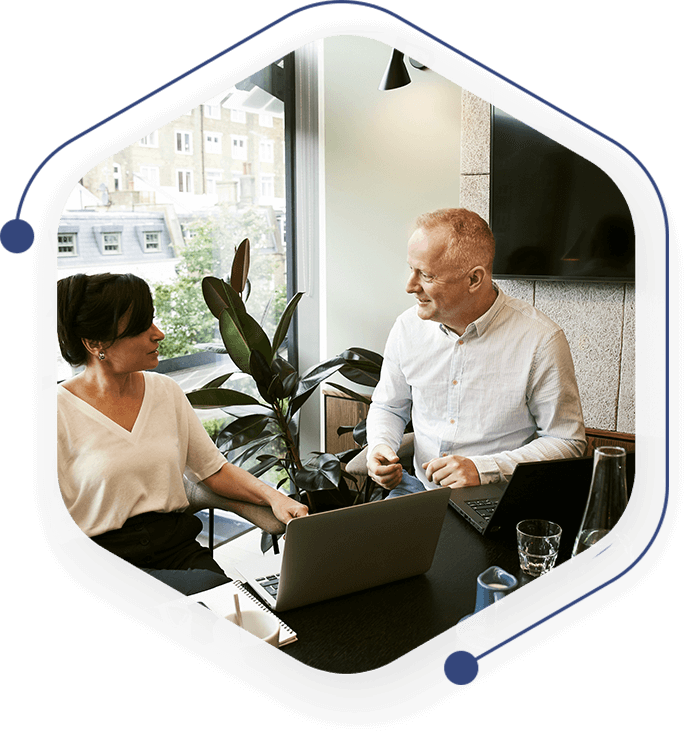 A man and woman are sitting at a table with a laptop.