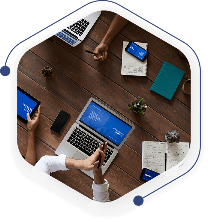 A group of people sitting around a table with laptops.