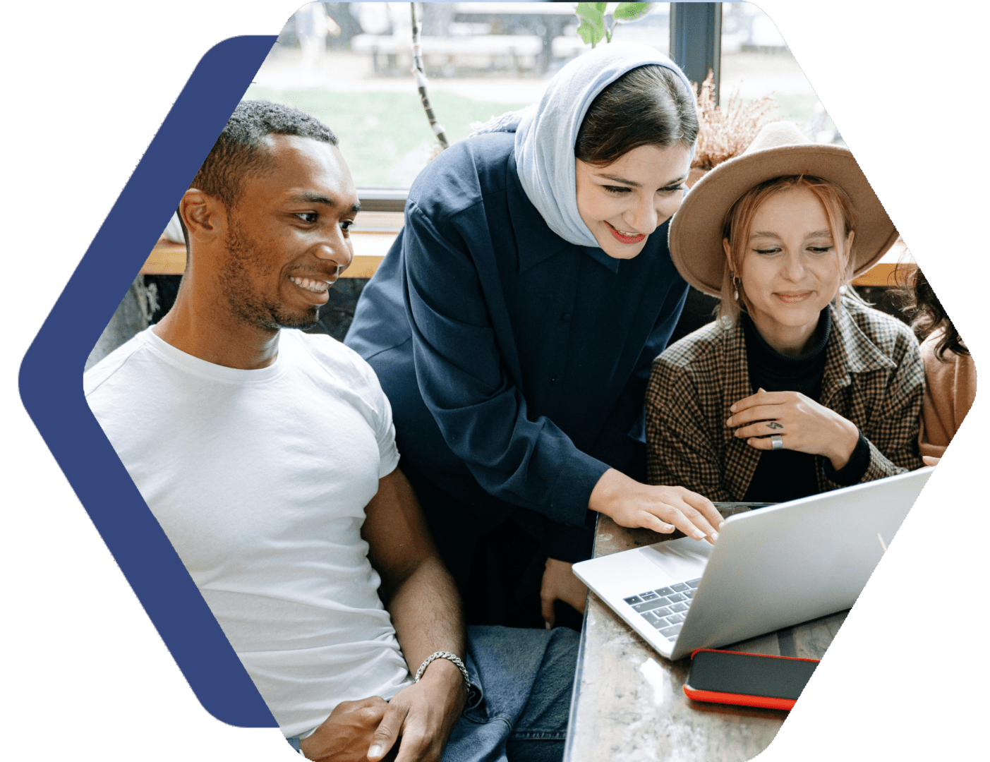 A group of people sitting around a table looking at a laptop.