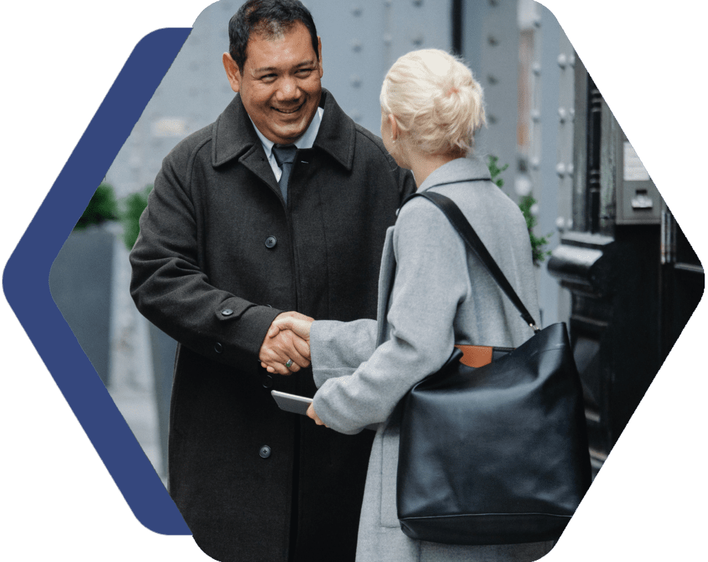 A man and woman shaking hands outside.